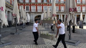 Waiters pack items after the town hall decreed the closure of the terraces at Mayor square in central Madrid, Spain, Friday, March 13, 2020. Exhibitions, conferences, sports centers and museums are closing in Madrid, including the Spanish capital's Prado Museum for the first time in eight decades.