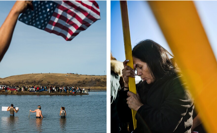 Protesters (left) wade into the Cannonball River as others (right) pray and hold flags while marching across a wooden pedestrian bridge across a creek north of the main protest camp near the Standing Rock Sioux Reservation.