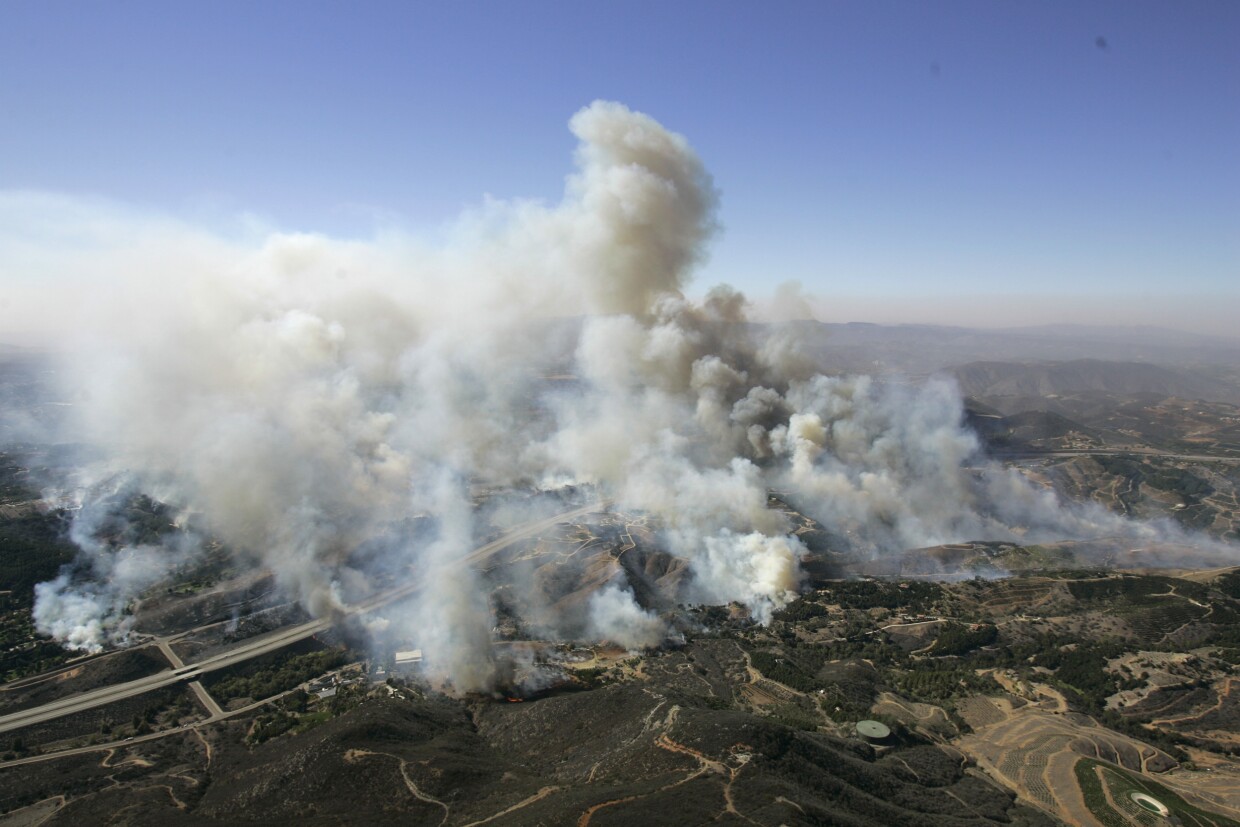 A firefighter works on hotspots as a helicopter drops water at a wildfire in Castaic, Calif., on Wednesday, Aug. 31, 2022.