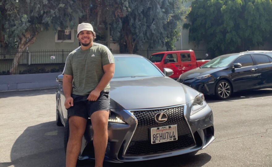 Johnny Navarro sits on the hood of his recently purchased 2014 Lexus.