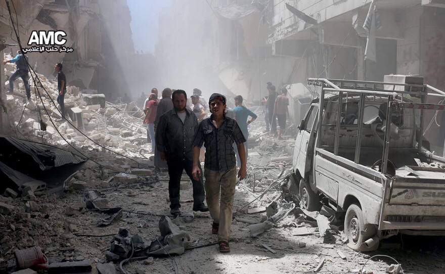 Syrian citizens inspect damaged buildings after airstrikes hit Aleppo, Syria in July, in a photo provided by the Syrian anti-government activist group Aleppo Media Center (AMC).