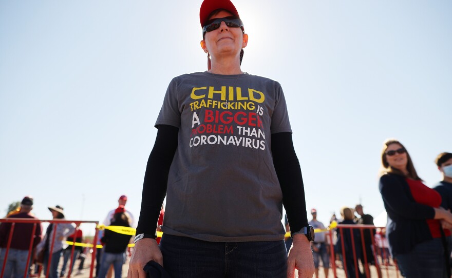 A woman wears a shirt promoting a QAnon conspiracy theory while waiting in line to attend a campaign rally with then-President Donald Trump on Oct. 28, 2020, in Goodyear, Arizona.