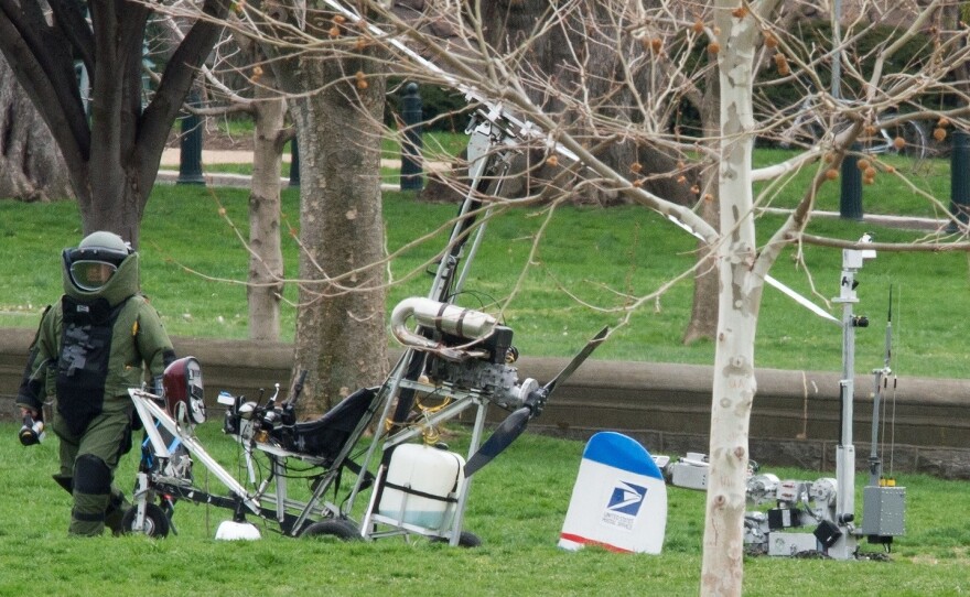 An Explosive Ordnance Disposal Technician and a robotic police device check Hughes' gyrocopter after it on the South Lawn of the Capitol.