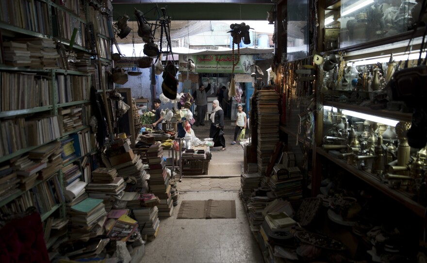 Palestinians pass by the Old Town Antique Store in Gaza's Old City, a shop brimming with dusty treasures, books, maps and ornaments.