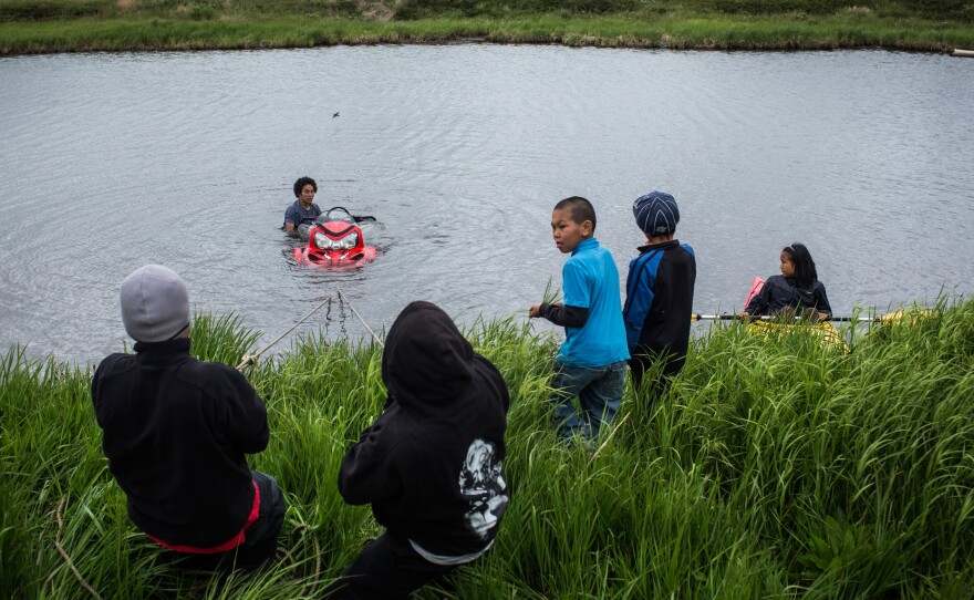 Yup'ik children help recover a snowmobile that sank when its owner attempted to drive across a pond, on June 30, 2015, in Newtok.