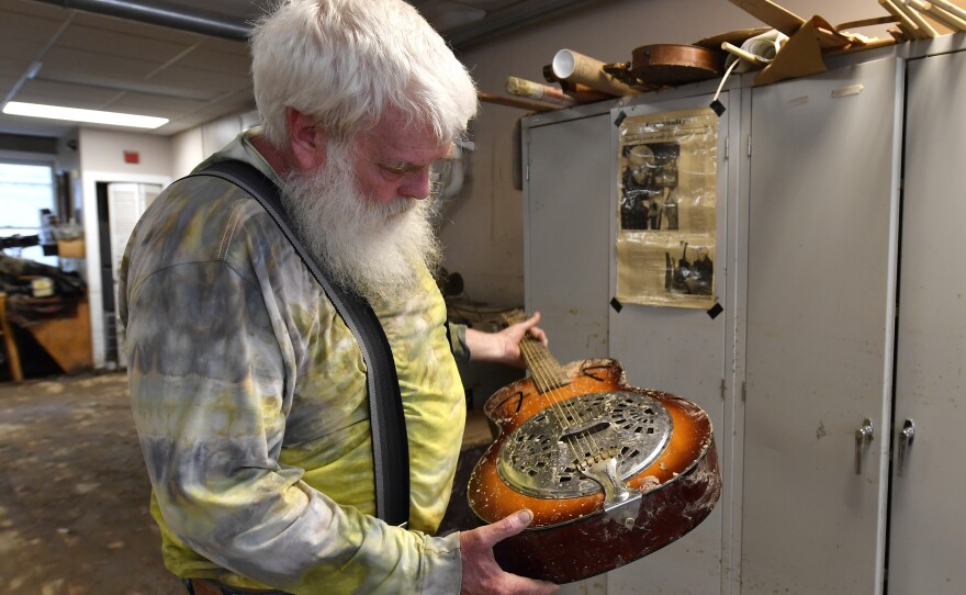 Paul Williams inspects the damage to a dobro guitar damaged by floodwaters from Troublesome Creek at the Appalachian School of Luthiery workshop and museum in Hindman, Ky., on Sunday.