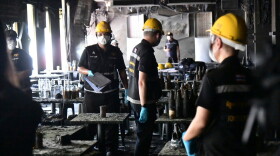 Rescuers carry the body of a victim of a fire in Bangkok, Thailand, Monday, July 13, 2026.