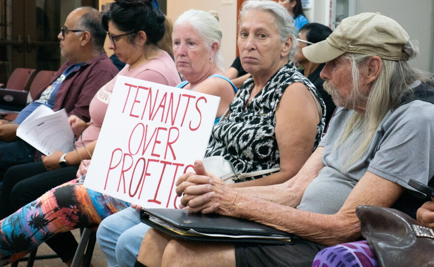 A community member holds a sign that reads "tenants over profits" at the Lemon Grove City Council meeting on July 21, 2026.