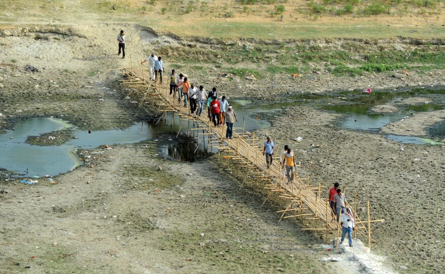 People cross a temporary bridge on a parched area of the Ganges River in Allahabad, India, on Thursday.