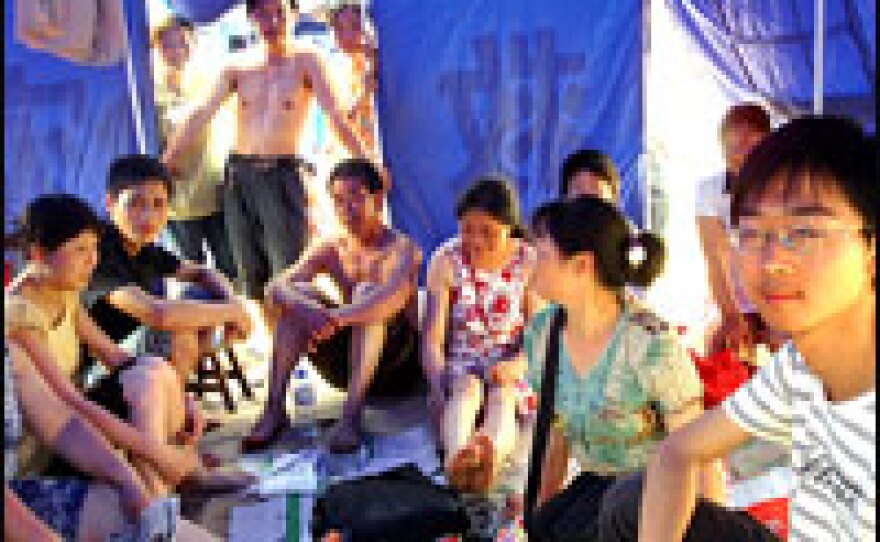 A 20-year-old English major at Mianyang University who goes by the name Frank shows NPR his family's blue tent in a tent city in Mianzhu. It was hot, humid and crowded.