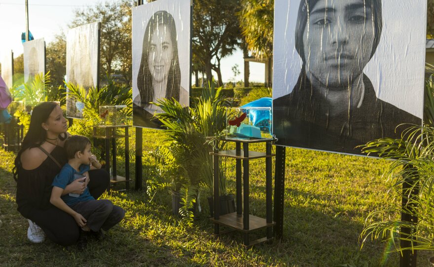 Mariana Rocha holds her son Jackson as she observes a photo of her cousin Joaquin Oliver at a memorial on the fifth anniversary of the Marjory Stoneman Douglas High School mass shooting.