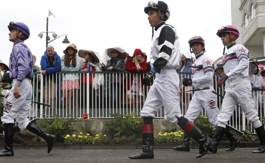 Jockeys walk through the paddock in a race before the 143rd running of the Kentucky Derby horse race at Churchill Downs on Saturday, in Louisville, Ky.