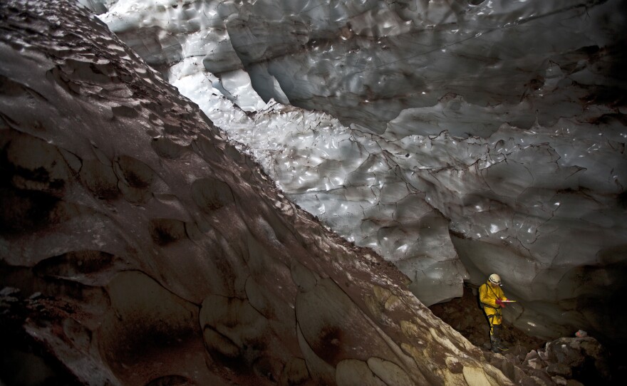 Mapping another world: An explorer writes down survey data in a glacier cave on Mount Hood.