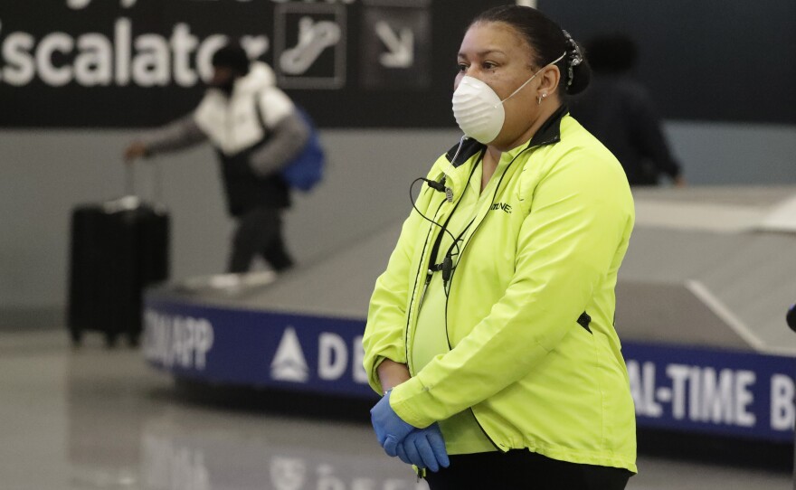 Customer service agent April Brown wears a protective mask and gloves as she helps people at the baggage claim at Hartsfield-Jackson Atlanta International Airport last month.