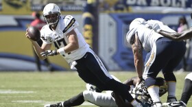 San Diego Chargers quarterback Philip Rivers is dragged down by Jacksonville Jaguars defensive end Ryan Davis while trying to release a pass during the second half of an NFL football game in San Diego, Sept. 28, 2014. 