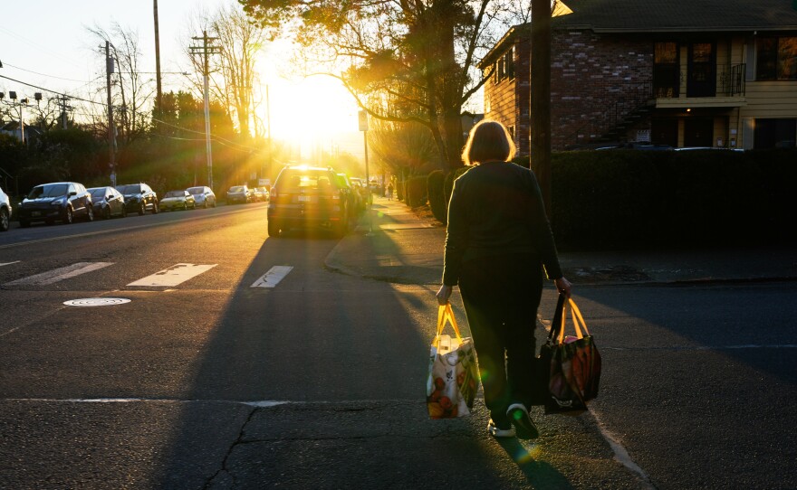 A woman carries reusable shopping bags to her car on Monday, March 16, 2026, in Portland, Ore.