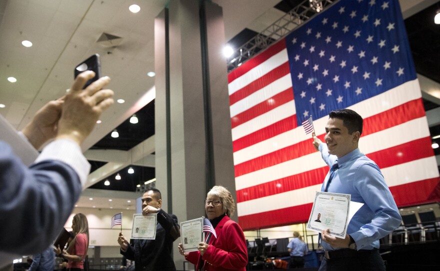 Immigrants pose with U.S citizenship certificates in front of a large U.S. flag after a naturalization ceremony at the Los Angeles Convention Center in February. A Supreme Court decision Monday will put the foreign-born children of unmarried American fathers on equal footing with those of unwed American mothers. That may mean longer waits for the latter, at least in the short term.