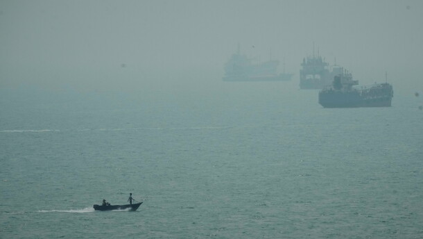 A motorboat travels past commercial vessels anchored amid haze in the Strait of Hormuz off Bandar Abbas, Iran, Monday, Sept. 7, 2026.