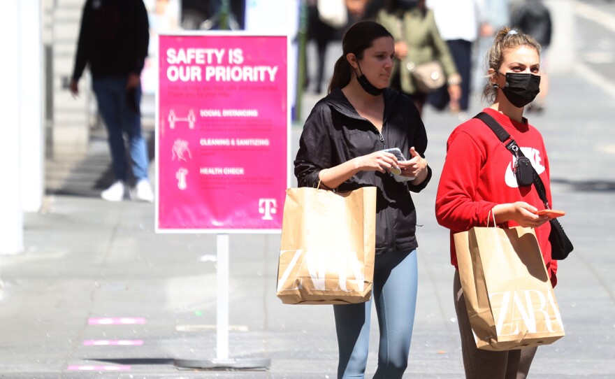 Pedestrians carry shopping bags as they walk through the Union Square shopping district on April 15 in San Francisco. Data on Friday showed personal income jumped 21.1% last month, in what was the largest increase on record.