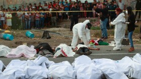 Bodies in bags sit on the side of the road after a deadly semi-trailer truck crash in Tuxtla Gutierrez, Chiapas state, Mexico, Dec. 9, 2021.