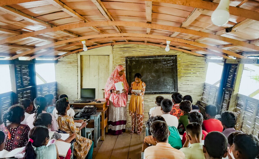 Hosne Ara teaches a group of fourth graders, seated on benches inside the floating school's classroom.
