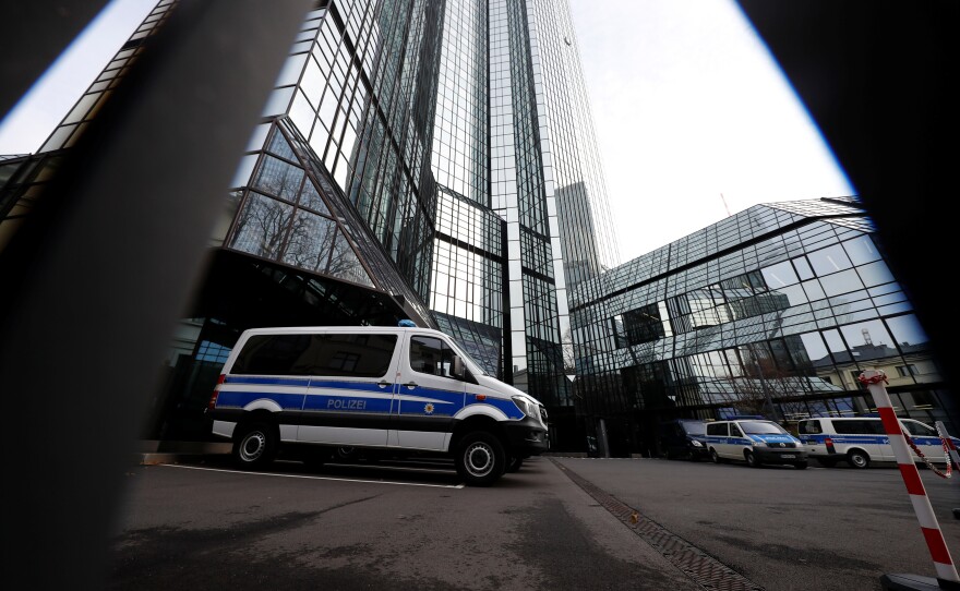 Police vehicles are parked in front of Deutsche Bank headquarters as roughly 170 officers, prosecutors and tax inspectors searched the bank's offices in and around Frankfurt, Germany, on Thursday.