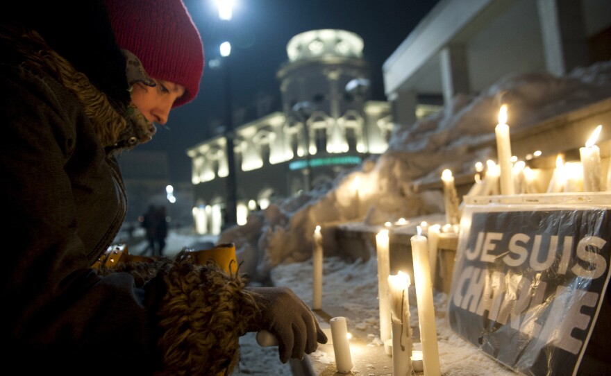 A Kosovo Albanian woman lights a candle next to an "I am Charlie" sign during a gathering in Pristina.