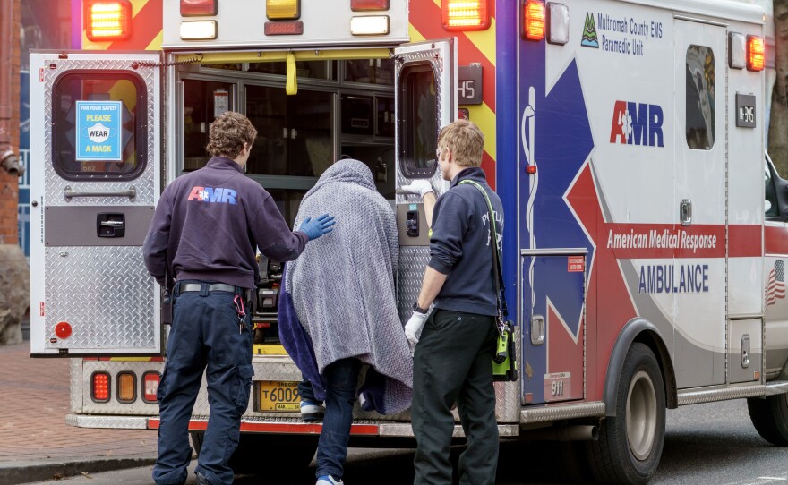 A man who was just revived from a near-fatal overdose climbs into the back of an ambulance.