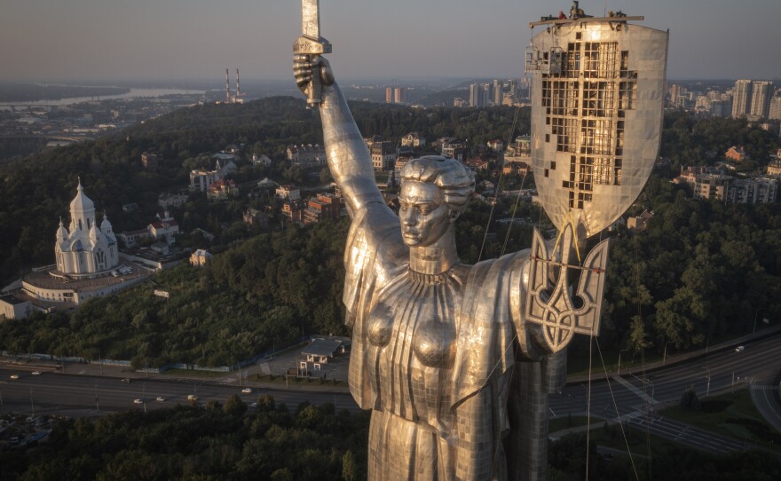 Workers install the Ukrainian coat of arms on the country's tallest statue, the Motherland Monument, after the Soviet coat of arms was removed, in Kyiv, Sunday. Ukraine is accelerating efforts to erase the vestiges of Soviet and Russian influence, pulling down monuments and renaming streets.