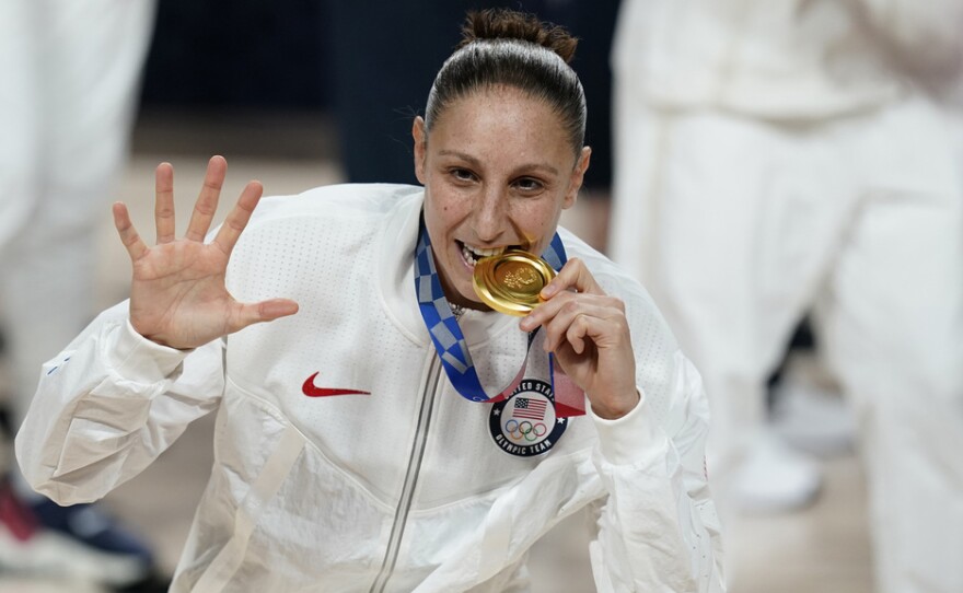 United States's Diana Taurasi bites her gold medal during the medal ceremony for women's basketball at the 2020 Summer Olympics, Sunday, Aug. 8, 2021, in Saitama, Japan. The 42-year-old guard will be playing in a record sixth Olympics when the U.S. goes for its eighth consecutive gold medal.