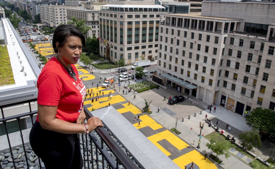 Mayor Muriel Bowser stands on the rooftop of the Hay-Adams Hotel near the White House and looks out at the words "Black Lives Matter" that have been painted in bright yellow letters on the street.