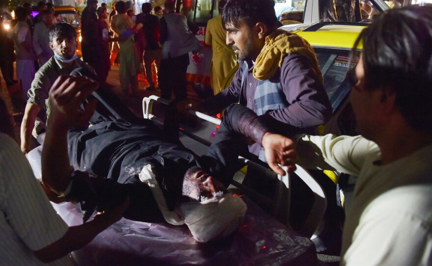 Medical and hospital staff bring an injured man on a stretcher for treatment after two blasts, which killed dozens of people, including U.S. service members, outside the airport in Kabul on Thursday.