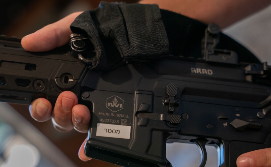 Ori Kahan, 21, a volunteer with an armed security squad in the central Israeli community of Rishpon, holds an assault rifle he keeps under his mattress in his bedroom.