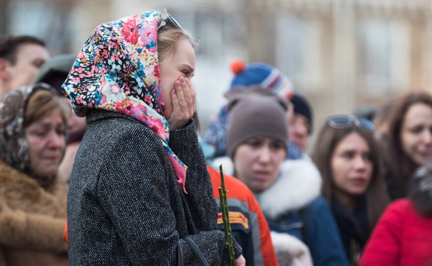 People gather outside the Zimnyaya Vishnya (Winter Cherry) shopping center to pay tribute to the victims of a fire that engulfed the mall on Sunday, killing at least 64 people. The building's alarm system reportedly had been shut off.