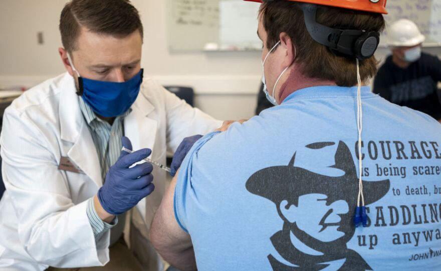 A pharmacist administers a dose of the COVID-19 vaccine to a worker at a processing plant in Arkansas City, Kan., on Friday, March 5, 2021. Researchers are concerned that vaccination rates in some rural communities may not keep up with urban rates.