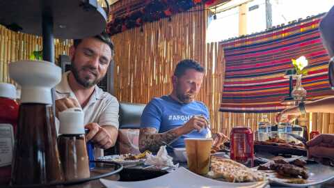 Sayed Naser, left, and Shawn VanDiver, right, eat lunch with friends and supporters in Lakeside on Oct. 2, 2025, in celebration of Naser's release from ICE detention. 