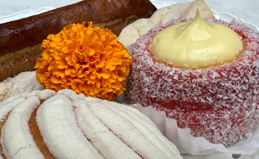A bright orange marigold flower is placed among different tradition Mexican pastries.