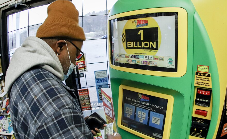 A patron, who did not want to give his name, uses the lottery ticket vending kiosk at a Smoker Friendly store to purchase tickets for the Mega Millions lottery drawing in Cranberry Township, Penn. The jackpot for the Mega Millions lottery game grew to $1 billion ahead of Friday night's drawing after months without a winner.