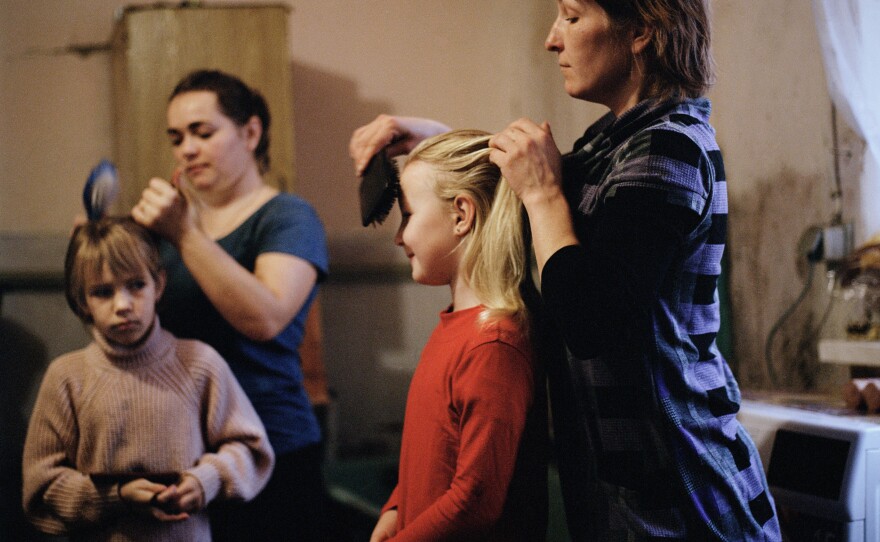 Olga Grinik (right) combing Miroslava's hair and Hanna Drobysh (left) combing her daughter Angelina's hair in their kitchen in Poltava region. December 2022.