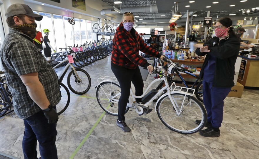 Store manager Josh Hayden, left to right, talks with Kay Amey and Jackie Gee about a new bicycle at Eddy's Bike Shop on Tuesday in Willoughby Hills, Ohio. Bike shops in most states were exempt from shutdown orders and sales have been up.