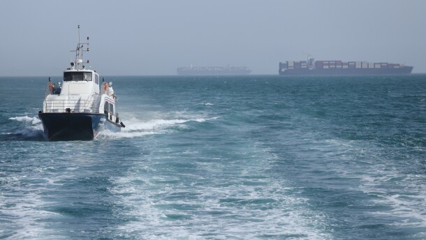 A patrol boat moves through the water as cargo ships sit at anchor in the Strait of Hormuz off Bandar Abbas, Iran, Saturday.