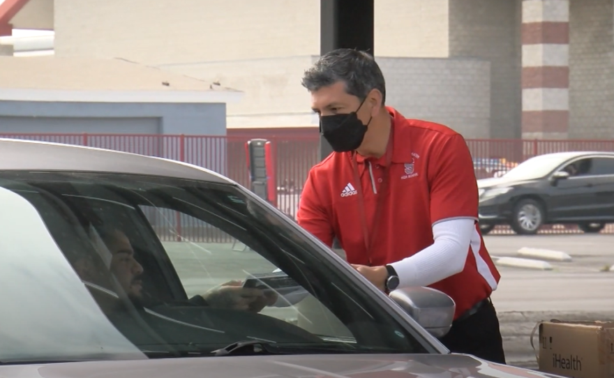 A Sweetwater High School staff member distributes a COVID-19 testing kit to a parent in the Sweetwater High School parking lot on January 7, 2022. 