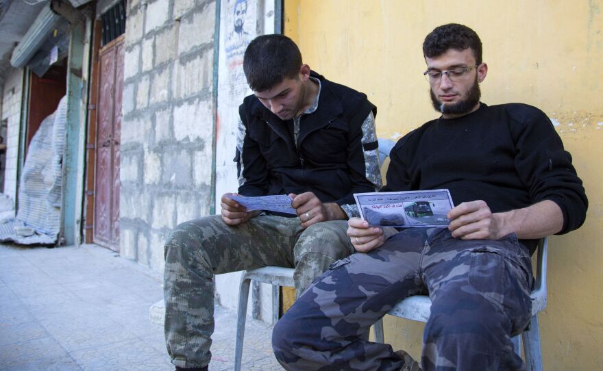 Opposition fighters in Aleppo look at fliers reportedly distributed by the Syrian government. The fliers encourage rebels to leave the eastern parts of the city. The Syrian army and its Russian ally have declared a "humanitarian pause," but there were few signs rebels or civilians were leaving.