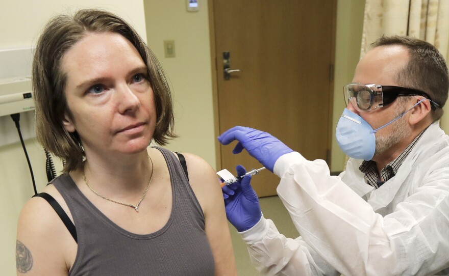 A pharmacist gives Jennifer Haller, left, the first shot in the first-stage study of a potential coronavirus vaccine on March 16, 2020, at the Kaiser Permanente Washington Health Research Institute in Seattle.