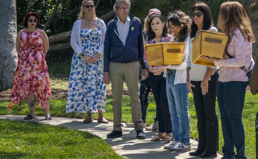 Each person in attendance holds the tiny coffin, one after the other, to honor the abandoned child who is being laid to rest at the Garden of Innocence, San Diego, June 17, 2023.<br/>