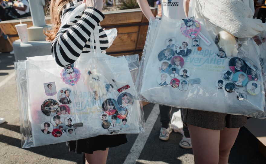 Two fans from Japan carry bags with pins of their favorite BTS members as they wait for the concert.