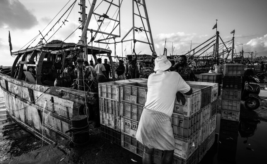 Workers gather beside a fishing boat at Kasimedu Fishing Harbour. built for fewer than 600 boats and now serving far more.