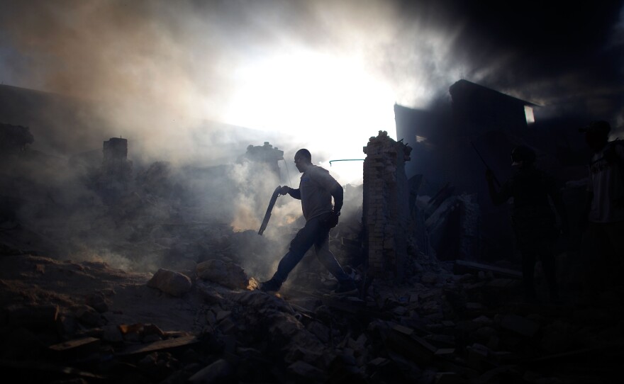 A man carrying a shotgun walks through a collapsed building while trying to keep looters at bay on the streets outside in the commercial district of downtown Port-au-Prince on January 18, 2010. Looters and scavengers ransacked destroyed buildings with little police presence.