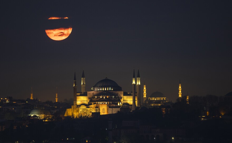 The moon appears over the Hagia Sophia and Suleymaniye Mosque in Istanbul on Tuesday.