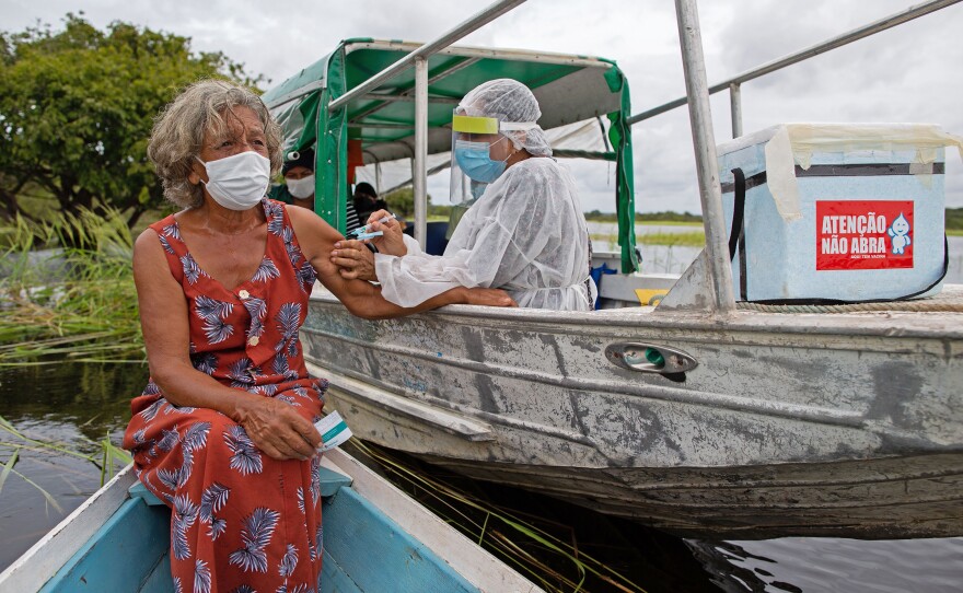 A health worker inoculates 72-year-old Olga D'arc Pimentel with a dose of Oxford-AstraZeneca's COVID-19 vaccine. She lives on the banks of the Rio Negro near Manaus, Brazil. A small study in South Africa has raised concerns about the AstraZeneca vaccine's effectiveness.
